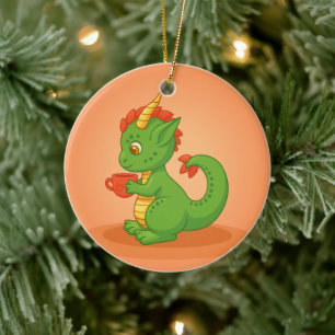 Schattige baby draak houdt kopje vast op oranje keramisch ornament