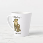 Schattige kikkertje in een rolstoel die positief i latte mok (Linkerhoek)