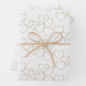 Schattigee gouden en zilveren hart charmes op wit inpakpapier vel (In situ)