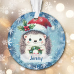 Schattigee Santa Hat Hedgehog kleinkind Ornament<br><div class="desc">Hier is een schattig kerstornament voor die speciale kleinzoon of kleindochter! Een kleine egel houdt een krans vast en draagt een rood en wit Santa Claus pet versierd met hulst en bessen. Het afbeelding wordt op een blauwe achtergrond geplaatst met witte sneeuwvlokken. De naam van je kind staat op een...</div>