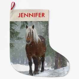 Schilderachtig bruine paarden in een winterbos met grote kerstsok