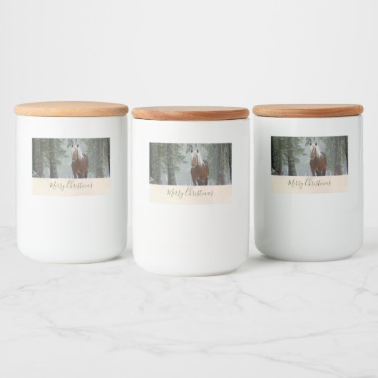 Schilderachtig bruine paarden in een winterbos met voedselcontainer etiket (Flessen)