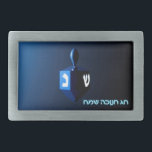 Shiny Blue Dreidel Gesp<br><div class="desc">Een modern,  metallic blauw model tegen een donkere,  nachtelijke achtergrond. Twee van de Hebreeuwse brieven vonden op een droidel,  nun en shin,  gloed helder. Hebreeuwse tekst met de tekst "Chag Chanukkah Sameach" (Happy Hanukkah) staat ook in blauw en wit gloeiend.</div>