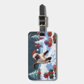 Siamees kat loopt in de sneeuw met kerstmuts bagagelabel (Voorkant verticaal)