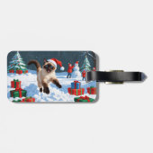 Siamees kat loopt in de sneeuw met kerstmuts bagagelabel (Achterkant horizontaal)