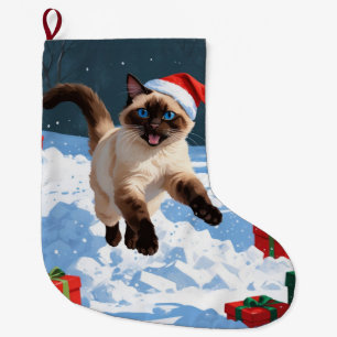 Siamees kat loopt in de sneeuw met kerstmuts grote kerstsok