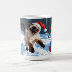 Siamees kat loopt in de sneeuw met kerstmuts koffiemok