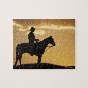 Silhouette van cowboy op horseback bij zonsonderga legpuzzel