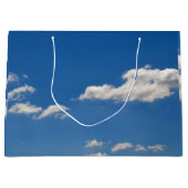 Sky is blauw en witte wolken gaan langs groot cadeauzakje (Voorkant)