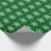 Sneeuwvlokken, bleke groene kristallen op donkergr cadeaupapier (Hoek)