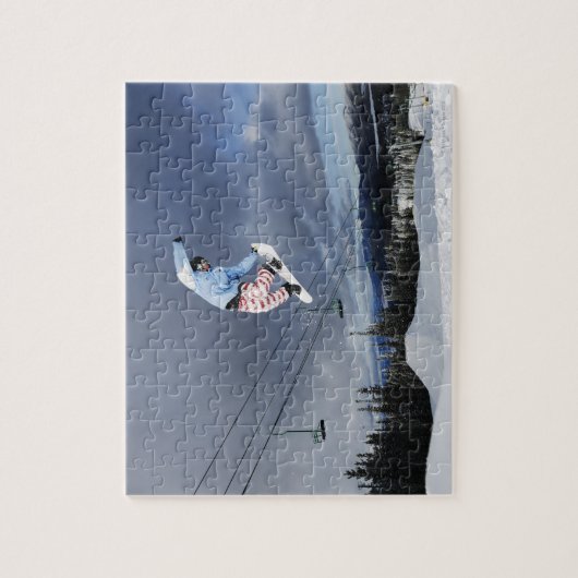 Snowboarder die in de lucht springt en een achterk legpuzzel (Verticaal)