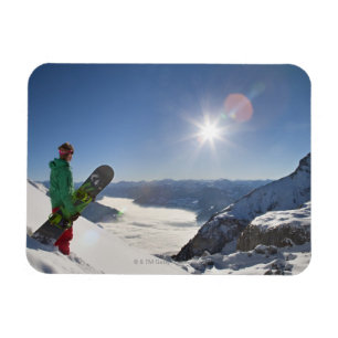Snowboarder kijkt van bergtop magneet