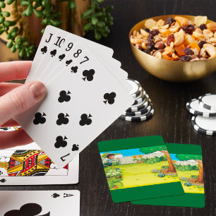 Speelse jongen die in een weelderige groene achter pokerkaarten