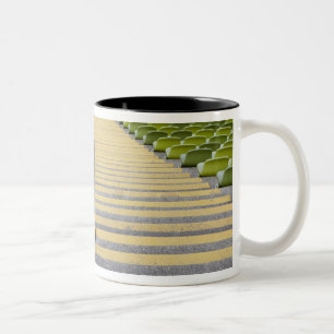 Stadiumtrap tussen rijen groene stoelen tweekleurige koffiemok