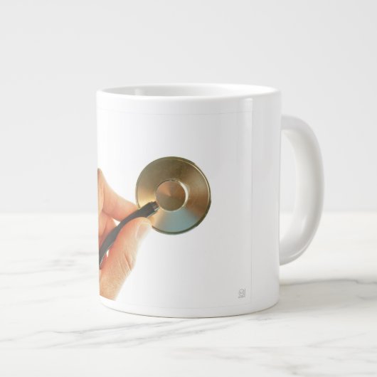 Stethoscoop in een hand voor een ziekenhuis sfeer. grote koffiekop (Voorkant rechts)