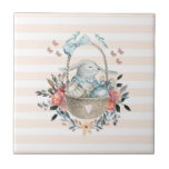 Stomme Bunny in een mand met eieren en  bloemen Tegeltje<br><div class="desc">Een keramische tegel met perzik en wit gestreept motief. Een digitale illustratie gemaakt met waterverven. Een charmant konijntje met een blauwe jurk in een mand omringd door haar eieren. Vlinders fladderen rond de mand die is versierd met een fancy bloemboeket.</div>