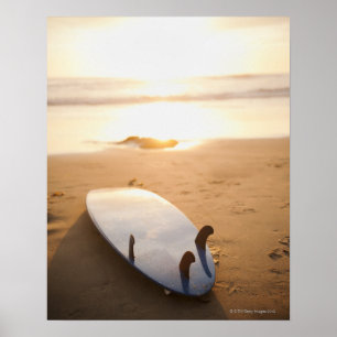 Surfbord op strand bij zonsondergang poster