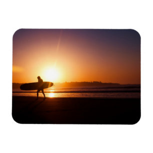 Surfer met surfplank op het strand bij zonsonderga magneet