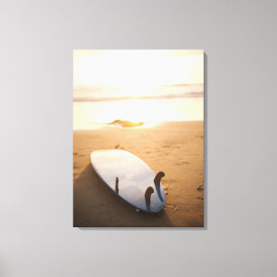Surfplank die op strand bij zonsondergang leggen canvas afdruk