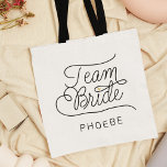 Team Bride Modern Script Gold Wedding Name Tote Bag<br><div class="desc">Deze moderne canvas tas met een minimalistisch casual ontwerp van het manuscriptcalligrafie die TEAM BRIDE lezen evenals de douanenaam van uw dienstmeisje van eer of bruidsmeisje kenmerkt schone lijnen aan creëer een gestroomlijnde en verfijnde verschijning. De ondergewaardeerde stijl met de kleine goudkleurige gouden hartdetails voegt een beetje verfijning toe aan...</div>