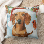 Teckel Winter Wonderland Christmas Joy Kussen<br><div class="desc">Dit feestelijke ontwerp vangt de vrolijke sfeer van het vakantieseizoen, met een schattige pup die een kerstmuts draagt. De hond is genesteld in een winterwonderland, compleet met een sneeuwpop, een versierde kerstboom en prachtig ingepakte cadeaus. Sneeuwvlokken herfsten zachtjes en voegen een magische toets toe aan het tafereel, terwijl de levendige...</div>