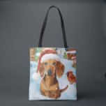 Teckel Winter Wonderland Christmas Joy Tote Bag<br><div class="desc">Dit feestelijke ontwerp vangt de vrolijke sfeer van het vakantieseizoen, met een schattige pup die een kerstmuts draagt. De hond is genesteld in een winterwonderland, compleet met een sneeuwpop, een versierde kerstboom en prachtig ingepakte cadeaus. Sneeuwvlokken herfsten zachtjes en voegen een magische toets toe aan het tafereel, terwijl de levendige...</div>