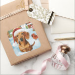 Teckel Winter Wonderland Christmas Joy Vierkante Sticker<br><div class="desc">Dit feestelijke ontwerp vangt de vrolijke sfeer van het vakantieseizoen, met een schattige pup die een kerstmuts draagt. De hond is genesteld in een winterwonderland, compleet met een sneeuwpop, een versierde kerstboom en prachtig ingepakte cadeaus. Sneeuwvlokken herfsten zachtjes en voegen een magische toets toe aan het tafereel, terwijl de levendige...</div>