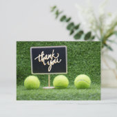 Tennisbal ligt op groen gras met karton bedankkaart (Staand voorkant)