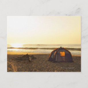 Tent en uitgebrand kampvuur op het strand. briefkaart