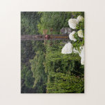The Garden Where Time Stands Still Legpuzzel<br><div class="desc">A peaceful scene where white hydrangeas bloom against a lush green forest, complemented by a vintage weather vane. Experience a quiet rest in a tranquil garden where the noise of daily life fades away.</div>