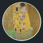 The Lovers Kissingembrace by Gustav Klimt Keramische Knop<br><div class="desc">Het zonlicht schittert door de wervelende gouden omhelzing die de geliefden omringt in Gustav Klimts meesterwerk, The Kiss. De scène is een paradox van intimiteit en isolatie. Het paar staat op een afgrond, een veld van kleurrijke bloemen aan hun voeten, maar ze zijn zich niet bewust van de wereld om...</div>
