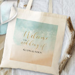 Tropical Sandy Ocean Beach Bruiloft Welkom Tote Bag<br><div class="desc">Bruiloft welkomsttassen met elegante gouden kalligrafie en waterverf strandscène. Design beschikt over een tropisch zandstrand met prachtige heldere oceaangolven die langs de kustlijn lopen. De sjabloon staat voor u klaar om de naam van de bruid en bruidegom toe te voegen. Voor het coördineren van items, zie mijn Boho Beach bruiloft...</div>