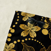 tropische bladeren en bloemen in goud op zwart strandlaken (In situ)