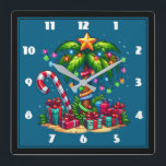 Tropische kerstpalmboom vierkante klok<br><div class="desc">Een klok met een seizoensgebonden vakantie afbeelding. Een tropische palmboom versierd in feestelijke lichten met een ster op de top. Een gigantische rode en witte suikerriet steken uit het zand. Kerstcadeautjes onder de boom. Grappig en leuk.</div>