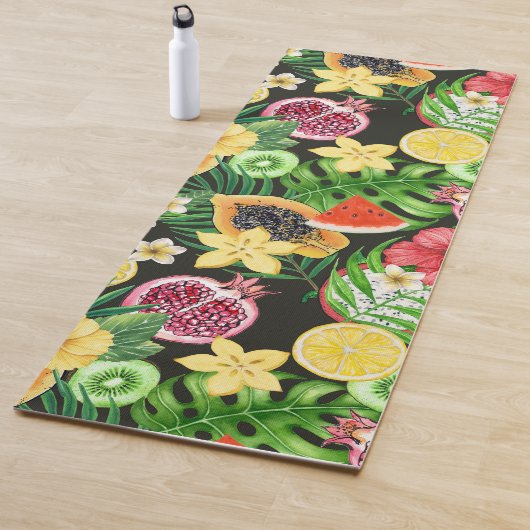 Tropische mix-fruit, bloemen en bladeren op zwart yogamat (In situ)