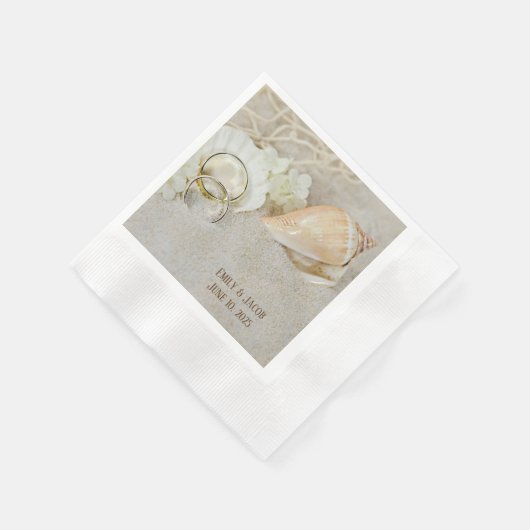 trouwringen en zeeschelpen in zand servet (Hoek)