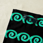 Turquoise en blauwe spiralen patroon op zwart strandlaken (In situ)
