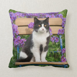 Tuxedo-kat op een tuinstoel met bloemen kussen