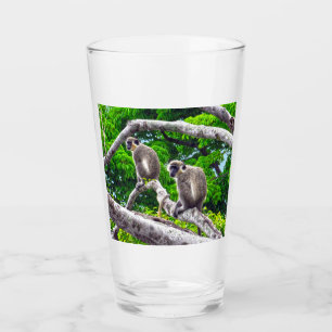 Twee groene apen die in een boomglas zitten glas
