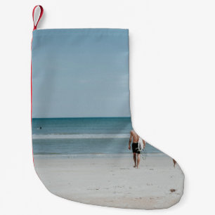 Twee personen die aan de kust lopen kleine kerstsok