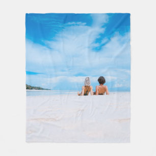 Twee vrouwen liggen op het witte zand onder het st fleece deken