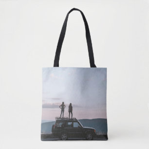 Twee vrouwen staan op het dak van de auto tote bag