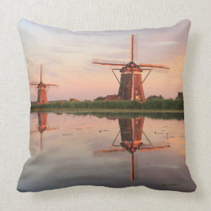Twee windmolens met reflectie bij zonsondergang kussen