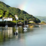 UITZICHTEN VAN WALES THEEDOEK<br><div class="desc">Na een dag regen komt de zon eindelijk uit en er komt een regenboog in de hemel, in dit prachtige landschap van de Aberdyfi-haven in Wales, met boten in het water en een aantal dorpshuizen.</div>