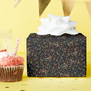 Verjaardagstaart strooit op zwart cadeaupapier