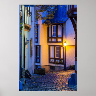 Verlichte straatlantaarn op een kasseienstraat poster