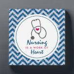Verpleegkunde is een werk van het hart Gezegde met Fotoplaat<br><div class="desc">Een fotoplaat met een blauw chevron faux glitter patroon. Niet echt glitter,  alleen een afbeelding. Lagen over de bovenkant is een wit lijst en binnenin is het gezegde: Verpleegkunde is een werk van het hart,  met een klein rood hart en een grijze stethoscoop.</div>