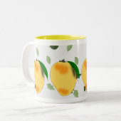 Verse sappige gele mango met groene bladeren tweekleurige koffiemok (Voorkant links)