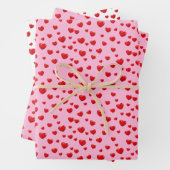 Verspreide rode harten op roze inpakpapier vel (In situ)