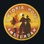 Vintage Travel, Victoria Hotel, Amsterdam, Holland Magneet<br><div class="desc">illustratie Europese reisposter kunst van het Victoria Hotel,  Amsterdam,  Nederland met een man en een vrouw in klederdracht en het dragen van klompen. Een zeilboot op de oceaan,  een gele zonsondergang en een traditionele windmolen liggen op de achtergrond achter een silhouet van een gelukkig stel.</div>